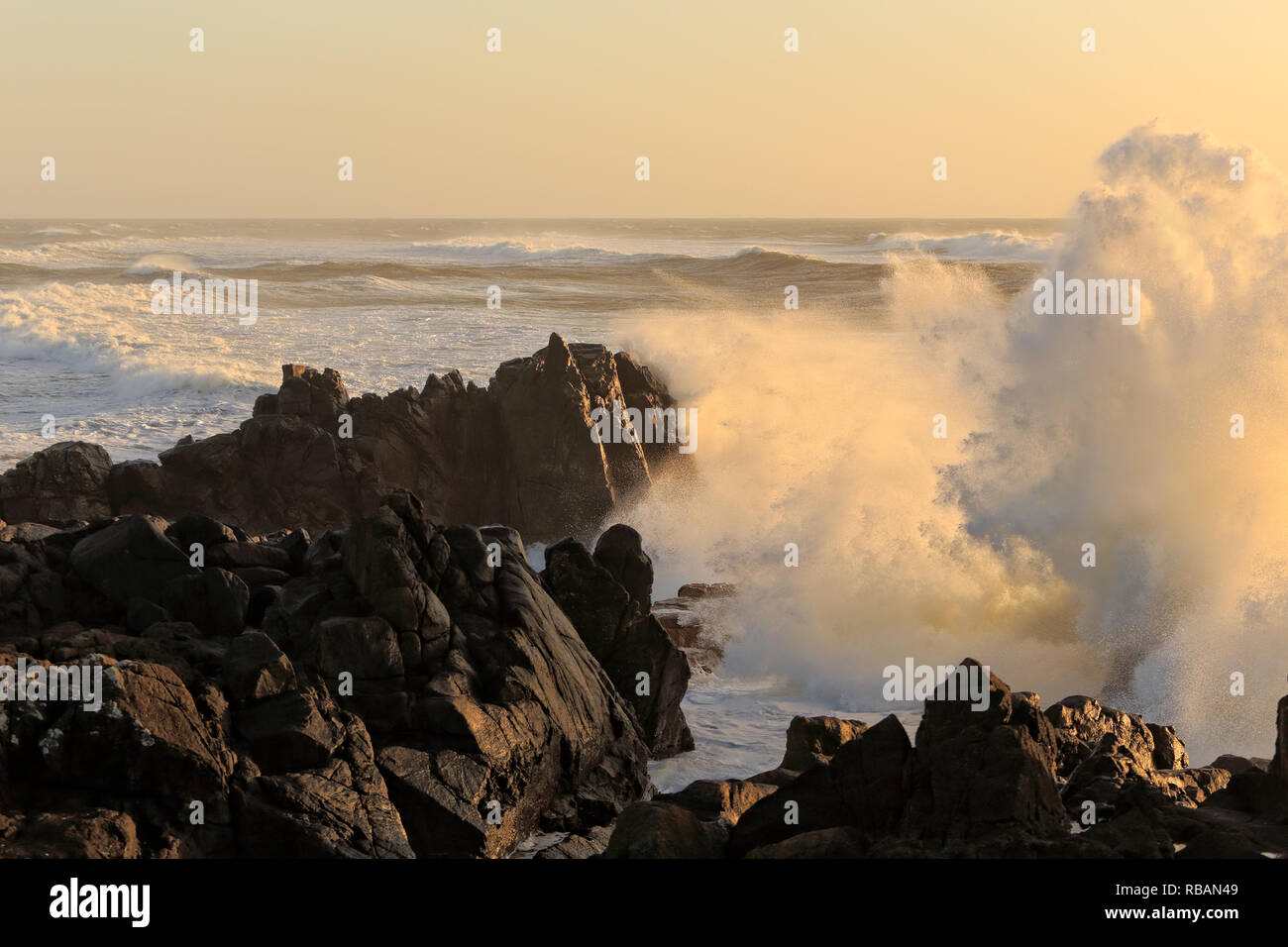 Tempesta di mare al tramonto con grandi onde contro la scogliera Foto Stock