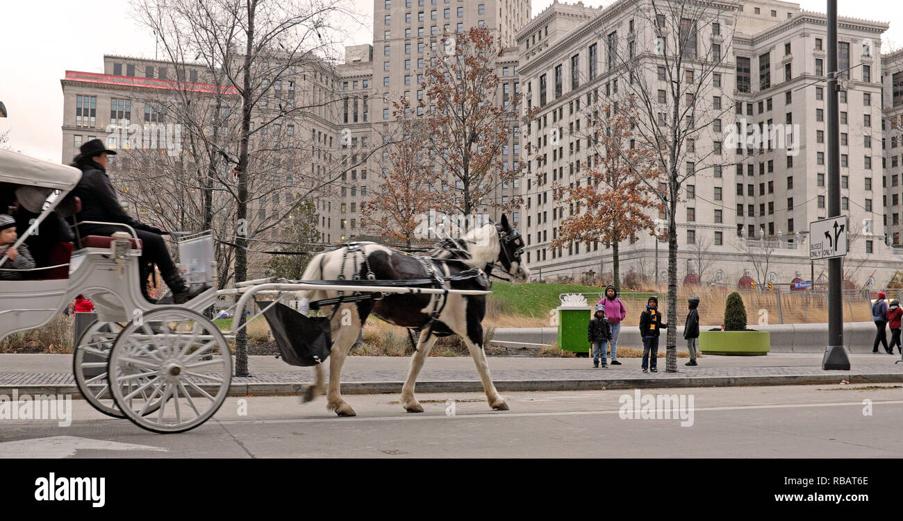 Un cavaliere diurno in carrozza trainata da cavalli si fa strada nella Public Square nel centro di Cleveland, Ohio durante le vacanze invernali. Foto Stock