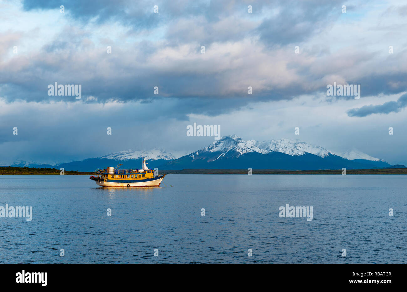 Paesaggio di l'ultima speranza del suono al sunrise con una barca da pesca e vette delle Ande picchi in background, Puerto Natales, Patagonia, Cile. Foto Stock
