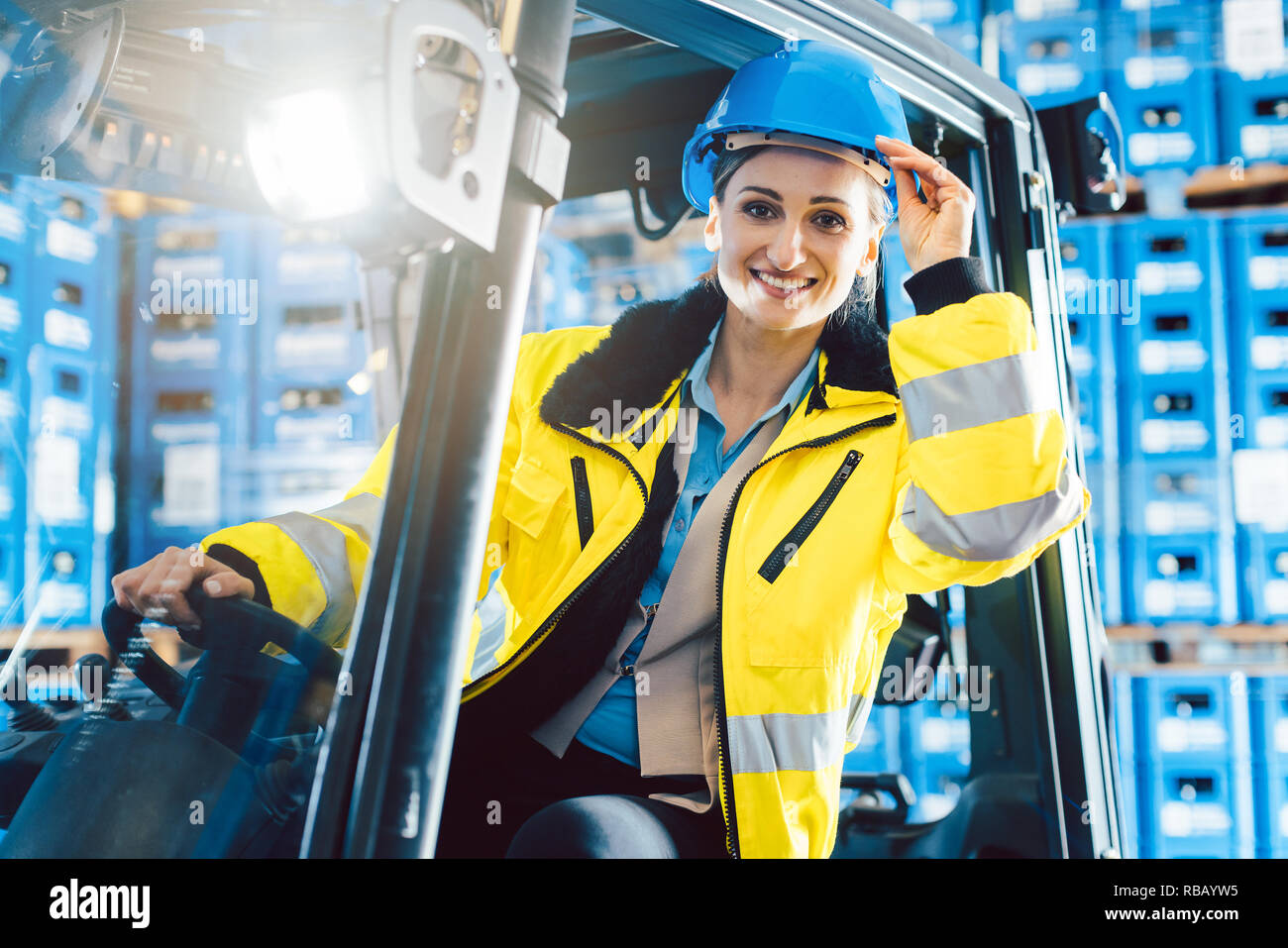 Donna alla guida di un carrello elevatore a forche nella logistica delivery center Foto Stock