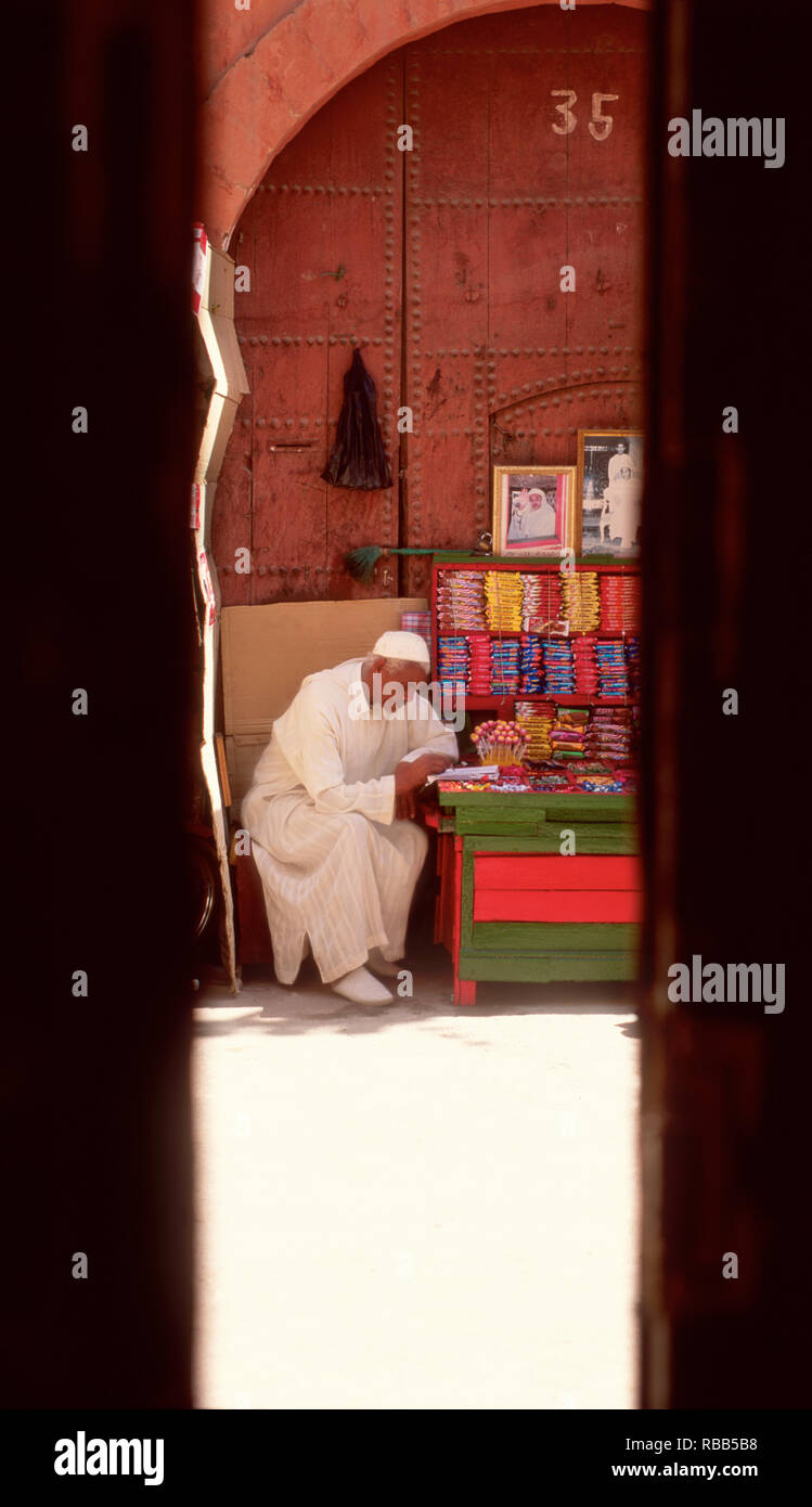 Un vecchio uomo è la lettura presso il suo negozio. Foto Stock