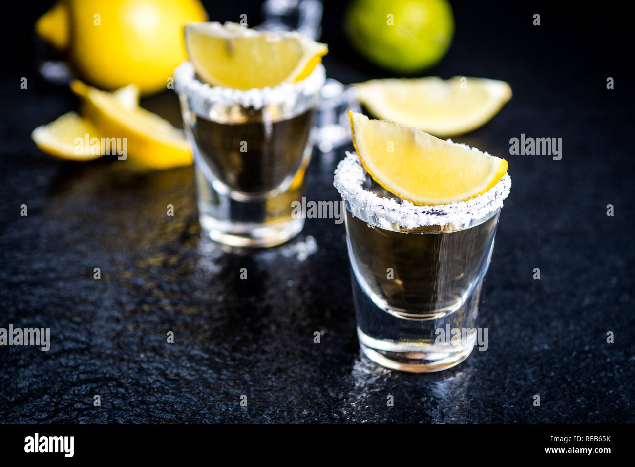 Tradizionale messicano Tequila con limone,sale e il cubo di ghiaccio sulla pietra scura tabella tabella Foto Stock
