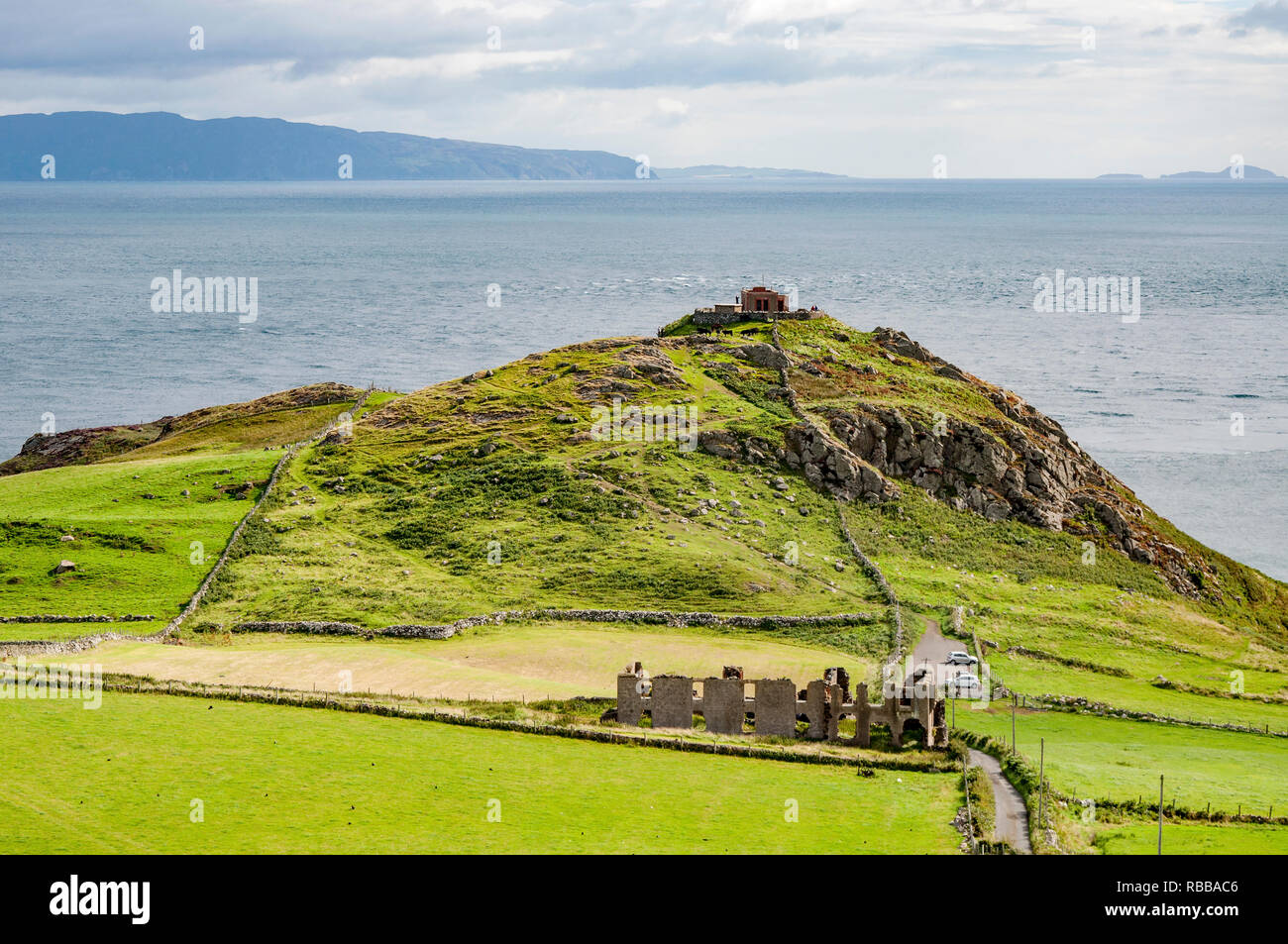 Torr capo operazioni automatiche di fine campo, scogliera rocciosa penisola e con le rovine della vecchia fortezza nella contea di Antrim, Irlanda del Nord, vicino a Ballycastle. Punto di vista lontano di Rathlin Island Foto Stock