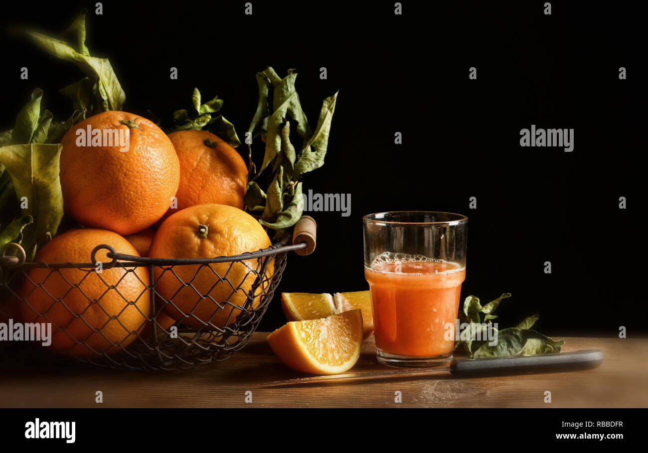 Succo di arance sul tavolo di legno con sfondo nero - primo piano Foto Stock