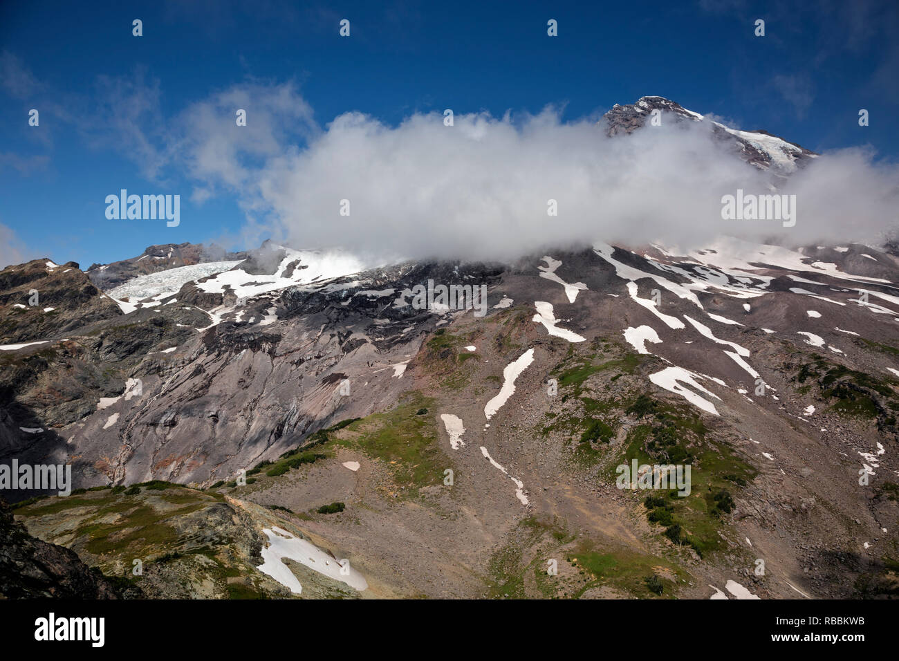 WA15683-00...WASHINGTON - Il successo dividono visto dalla Piramide di picco e la vetta del Monte Rainier creando proprie nuvole in Mount Rainier Nationa Foto Stock