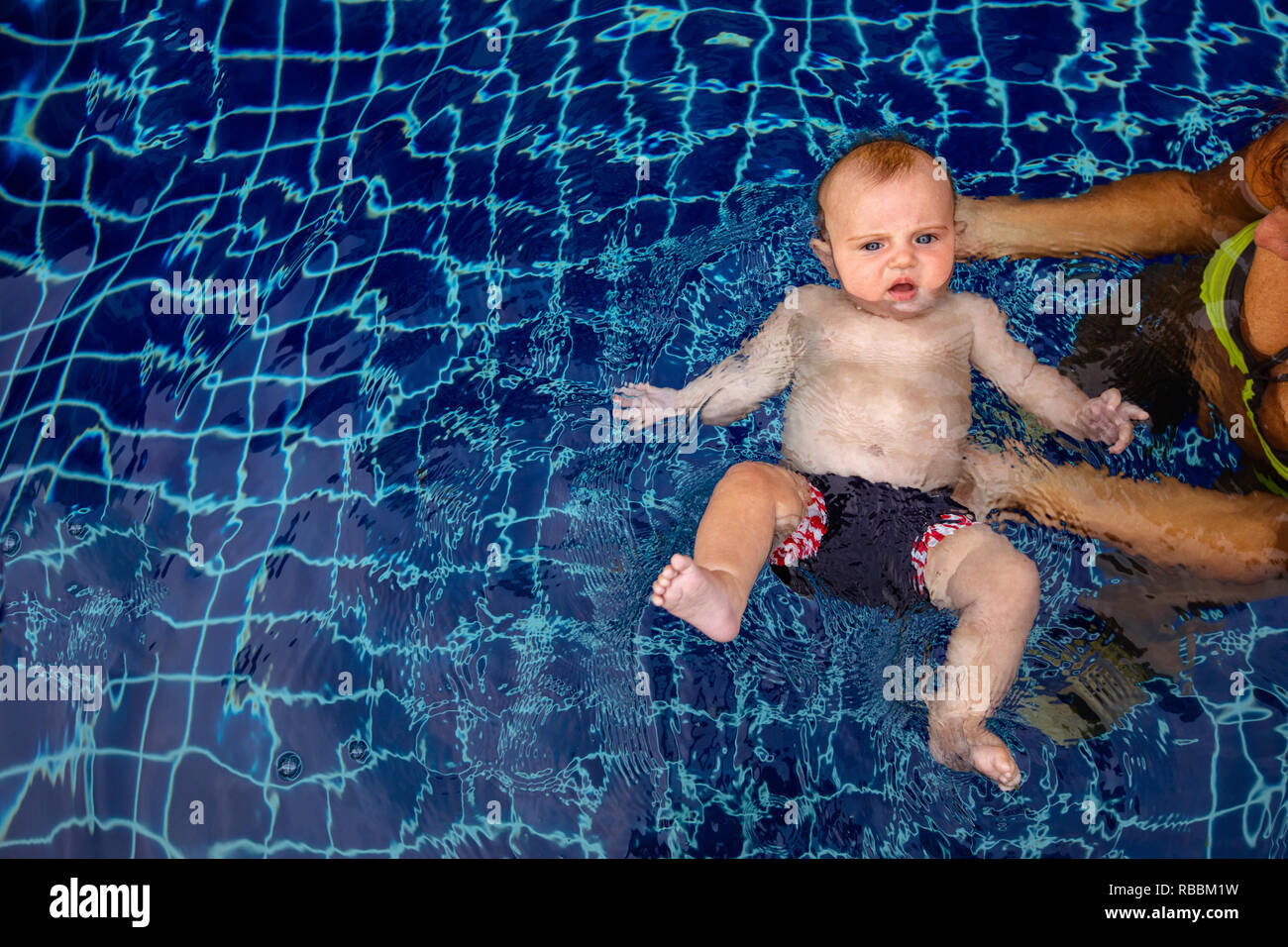 Little Boy di nuoto in piscina con un genitore Foto Stock