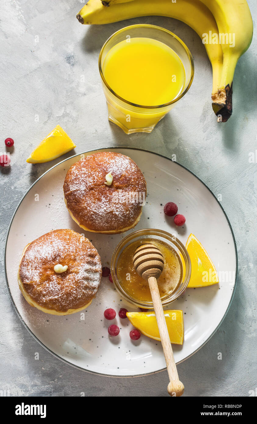 Ristorante e bar Colazione La colazione è servita con succo di arancia, donut e frutti su sfondo di calcestruzzo Foto Stock