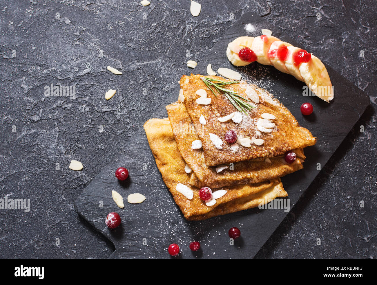 Crepes tradizionali con banana e bacche nere su sfondo di pietra. Spazio di copia Foto Stock