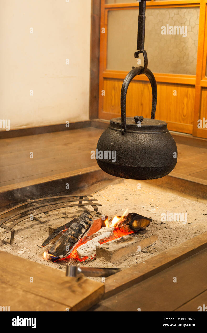 Giapponese bollitore in metallo appesa sopra un fuoco aperto in casa giapponese. Foto Stock