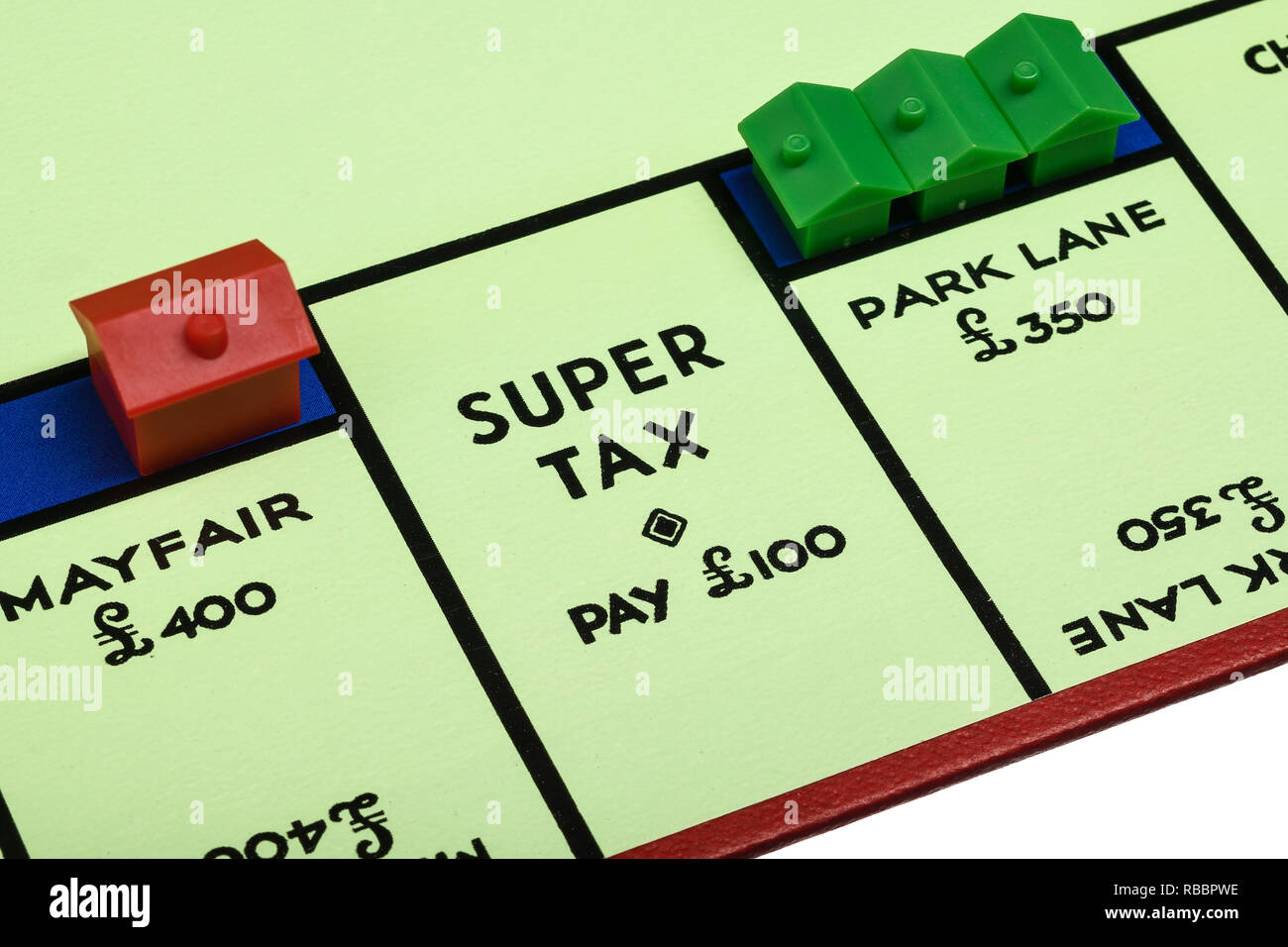 Close up dettaglio della riproduzione di bordo per il gioco del Monopoli che mostra Super imposta pagare £100 Foto Stock