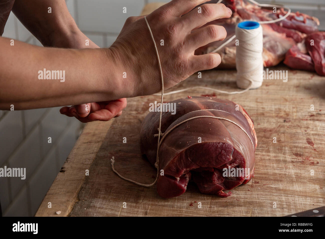 Butcher prepara la carne di cervo a Gog Farm Shop, Stapleford, Cambridge, Cambridgeshire Foto Stock