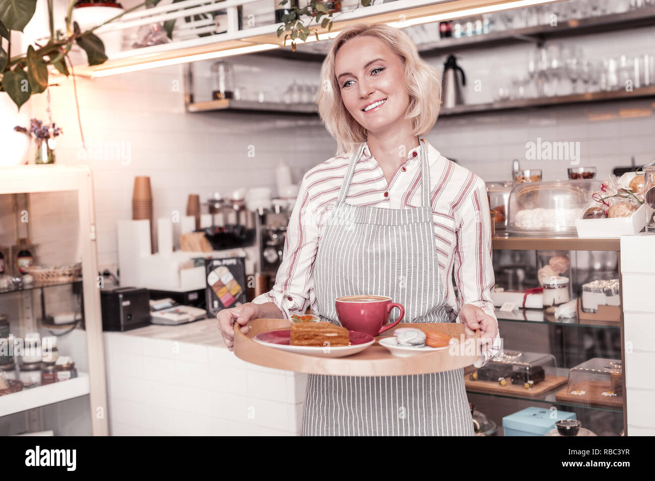 Positivo donna gioiosa lavora come cameriera Foto Stock