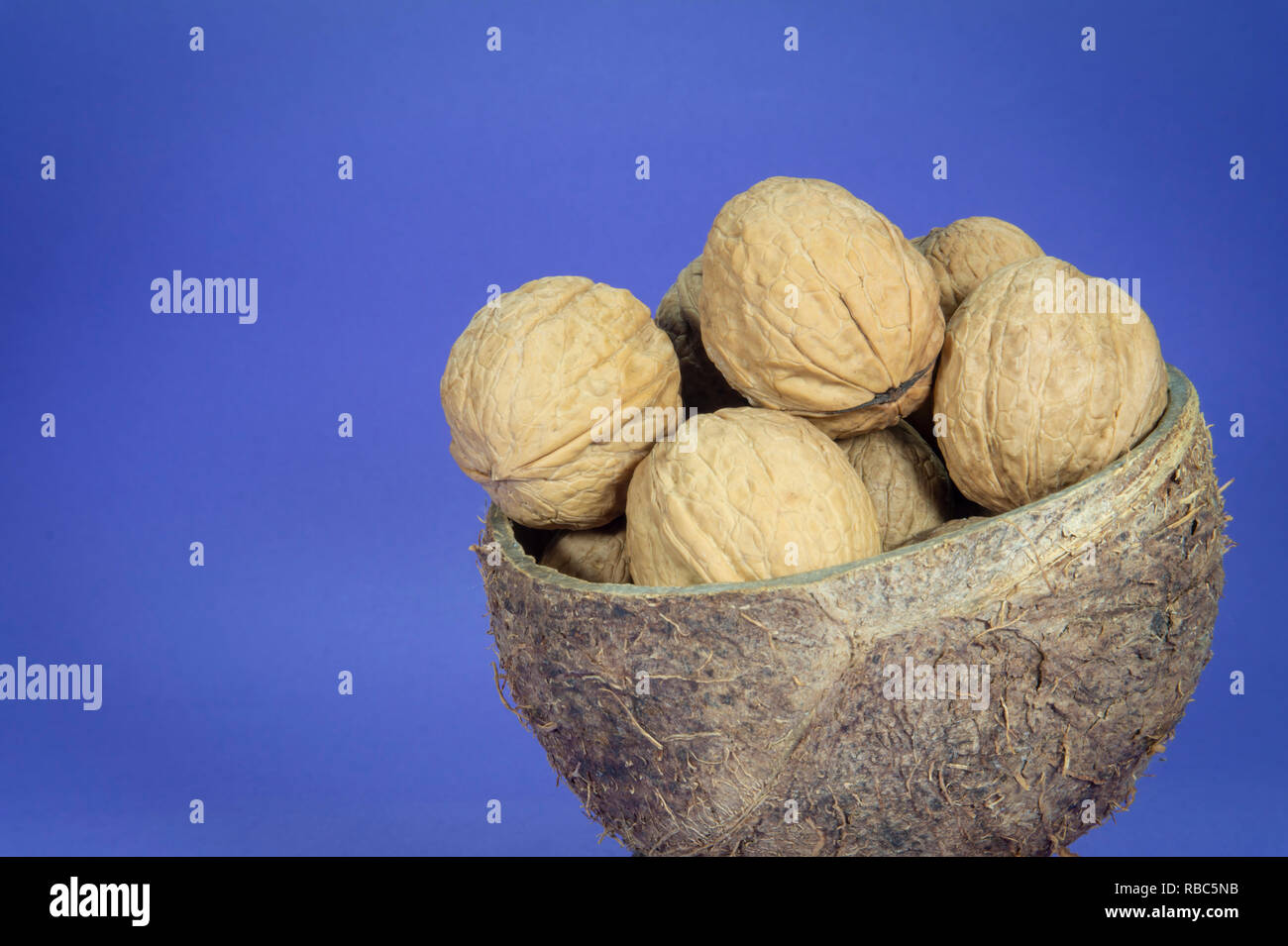 Pila di tutta le noci comuni con guscio di noce di cocco naturale Coppa Shell sul luminoso sfondo blu Foto Stock
