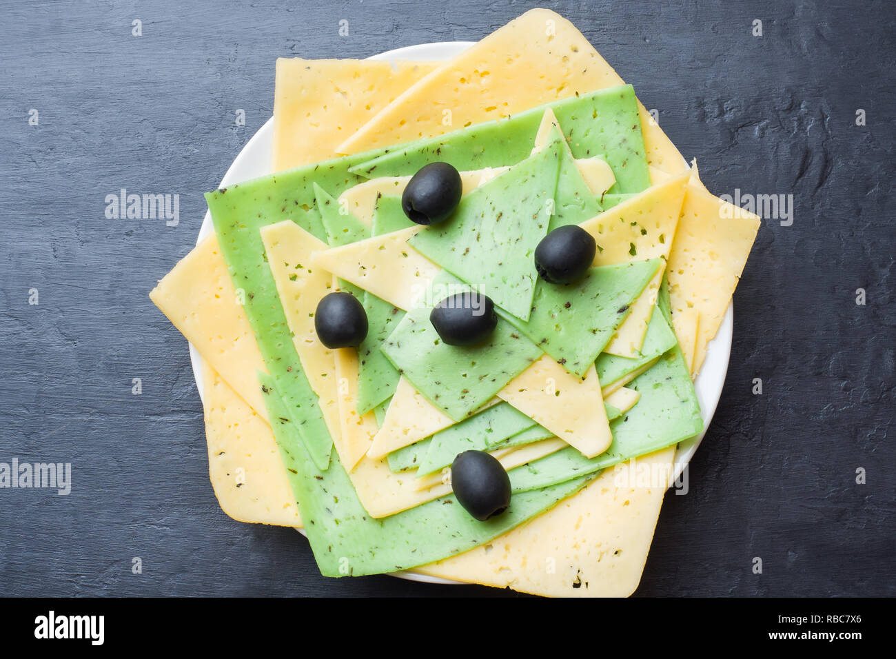 Diversi tipi di formaggio sono tagliati su una piastra con olive. Foto Stock