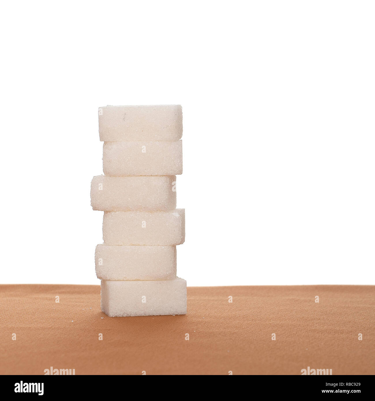 Pila di sei cubetti di zucchero sul tessuto, sfondo bianco. Consigliata giornaliera importo massimo. Foto Stock
