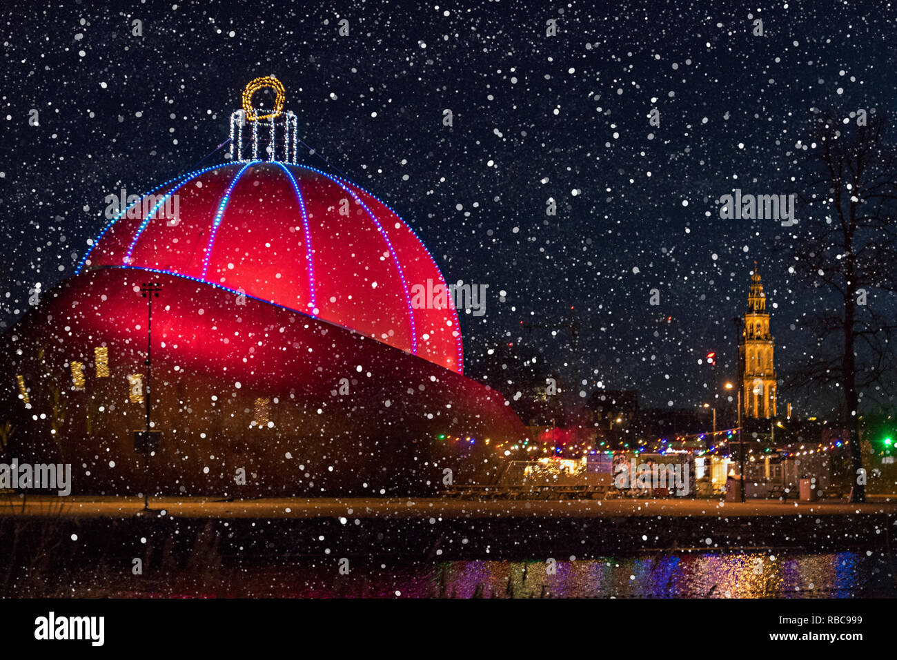 Edificio illuminati come un rosso edificio di natale di notte con la neve a Groningen Foto Stock