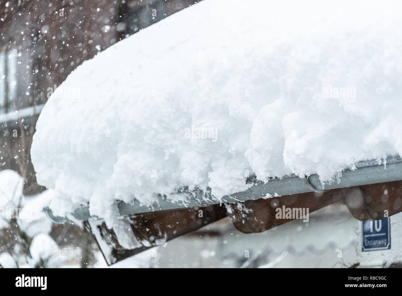 Snow Drift sul tetto dopo due giorni di nevicate. Strati spessi appeso sul tetto di casa. Germania Baviera Foto Stock