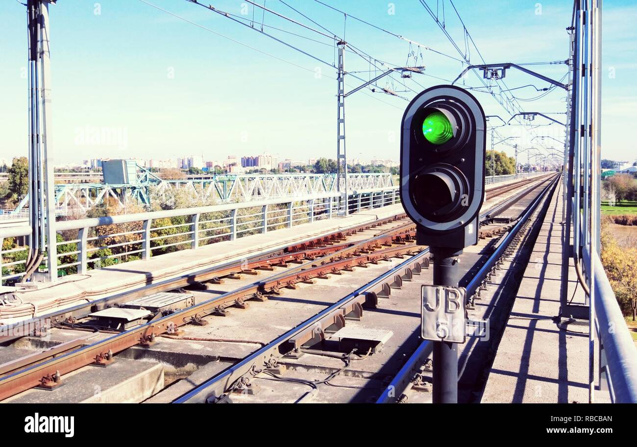 Semaforo verde sulla metropolitana le vie con catenarie su piste e il cielo blu in background Foto Stock