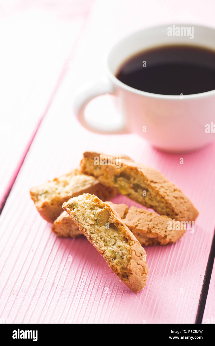 Dolce cantuccini biscotti. Biscotti italiani e la tazza di caffè sul tavolo di colore rosa. Foto Stock