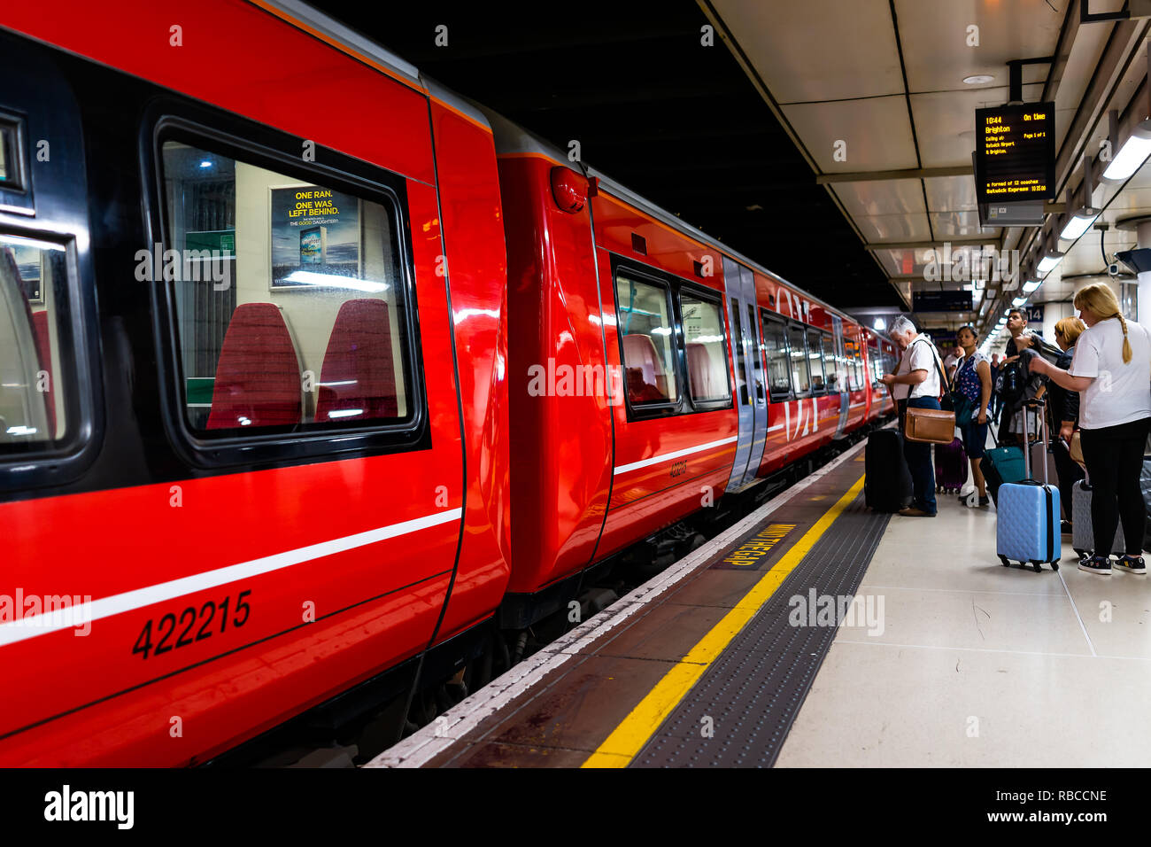 London, Regno Unito - 28 Giugno 2018: Gatwick Express metro con la metropolitana rossa in treno stazione di London Victoria, persone in attesa sulla stazione della piattaforma Foto Stock