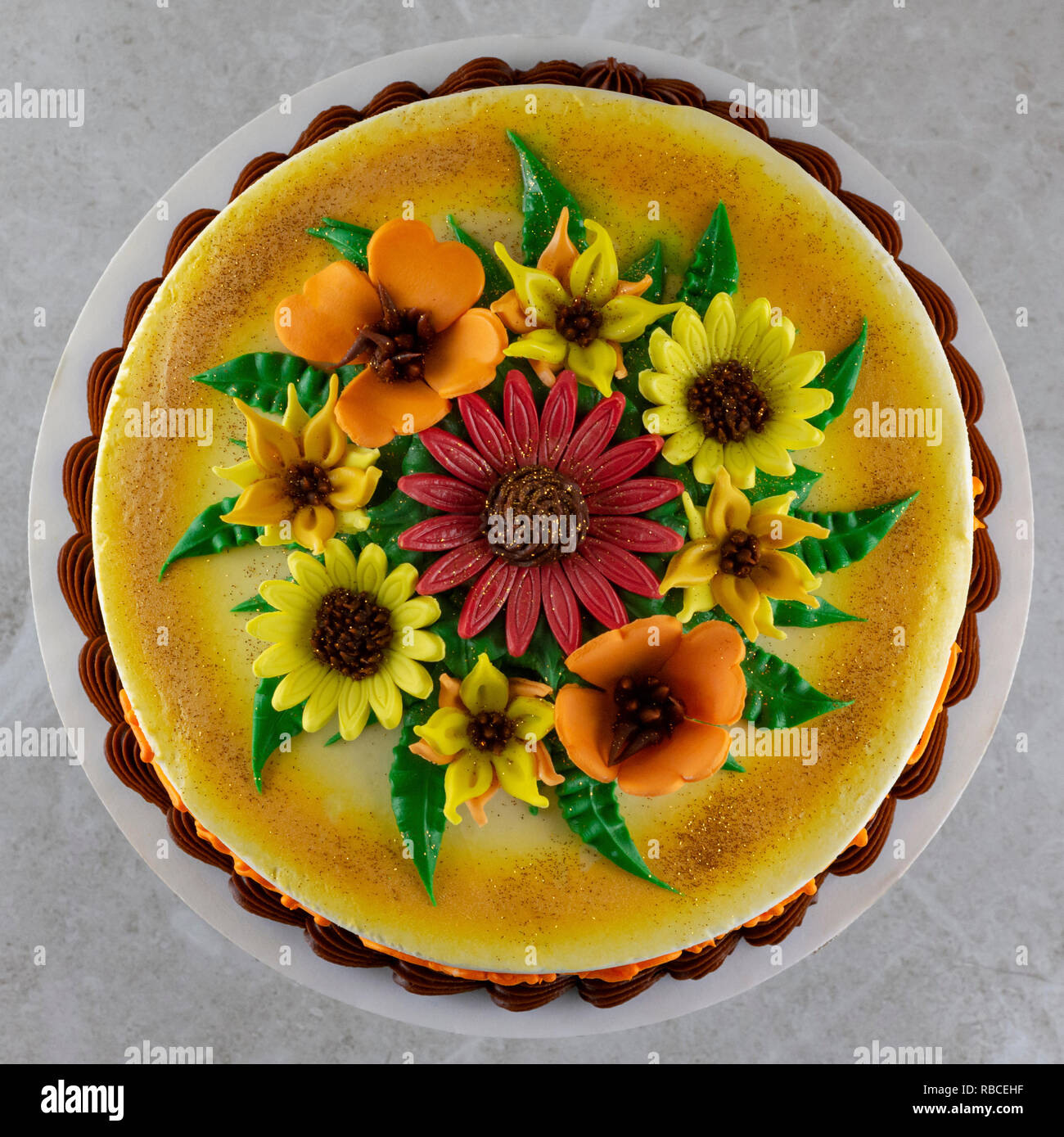Scatto dall'alto di una torta decorata con fiori di fondente e spolverati con glitter commestibile. Foto Stock