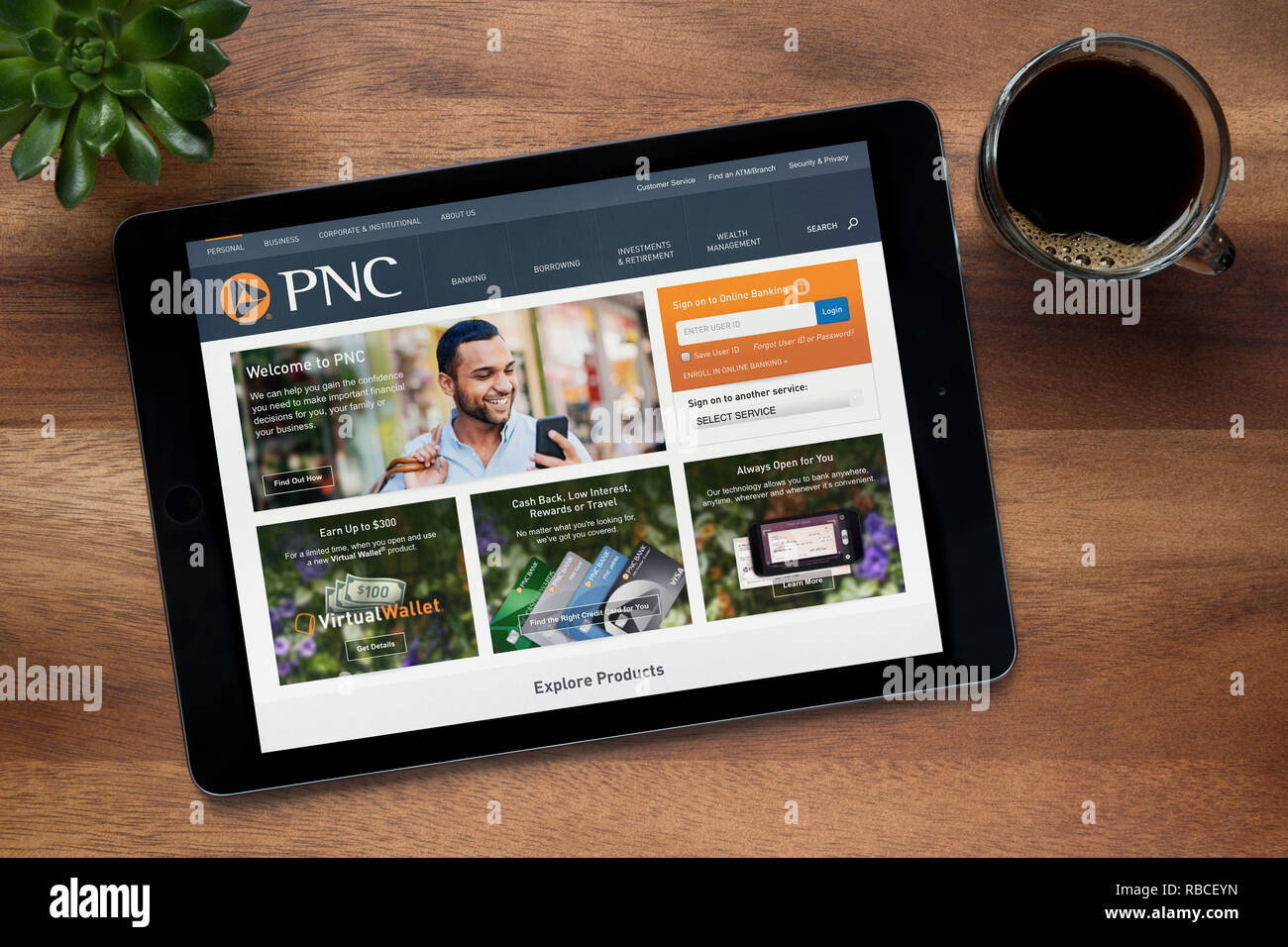 Il sito web di PNC Financial Services è visto su un tablet iPad, su di un tavolo di legno lungo con un caffè espresso e una pianta di casa (editoriale solo) Foto Stock
