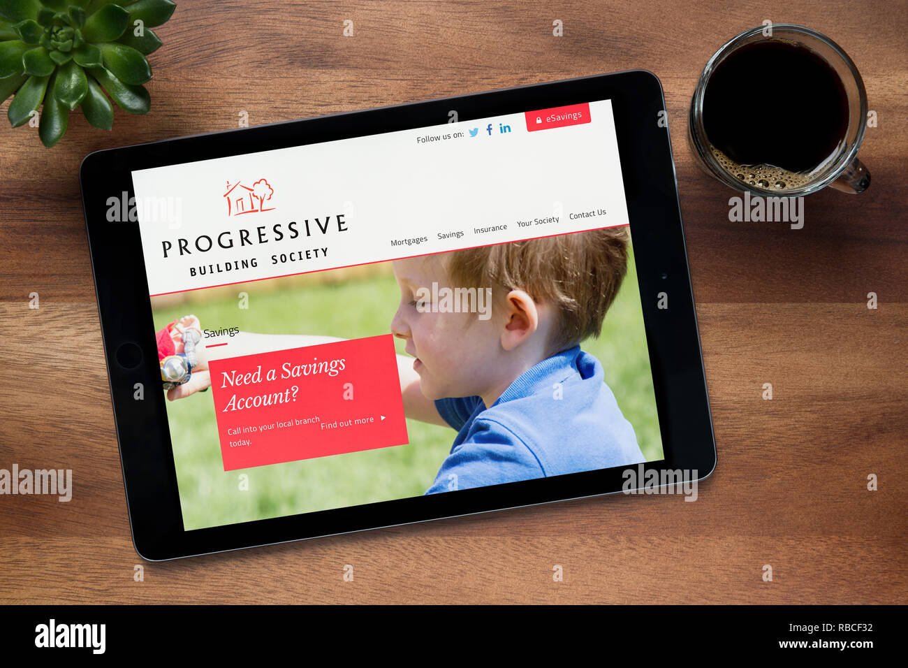 Il sito web di progressiva costruzione della società è visto su un tablet iPad, appoggiato su una tavola di legno (solo uso editoriale). Foto Stock