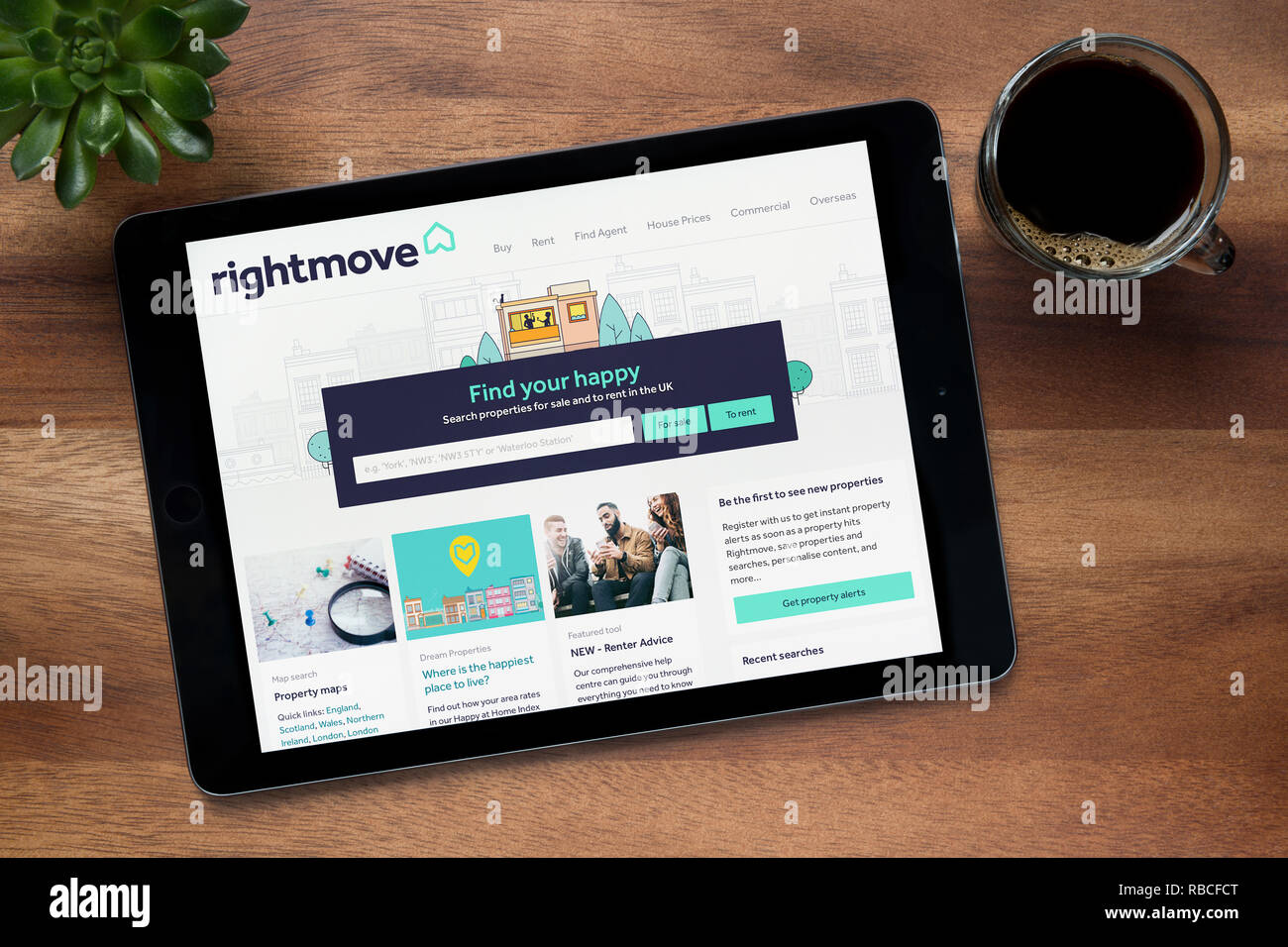 Il sito web di Rightmove è visto su un tablet iPad, su di un tavolo di legno lungo con un caffè espresso e una pianta di casa (solo uso editoriale). Foto Stock