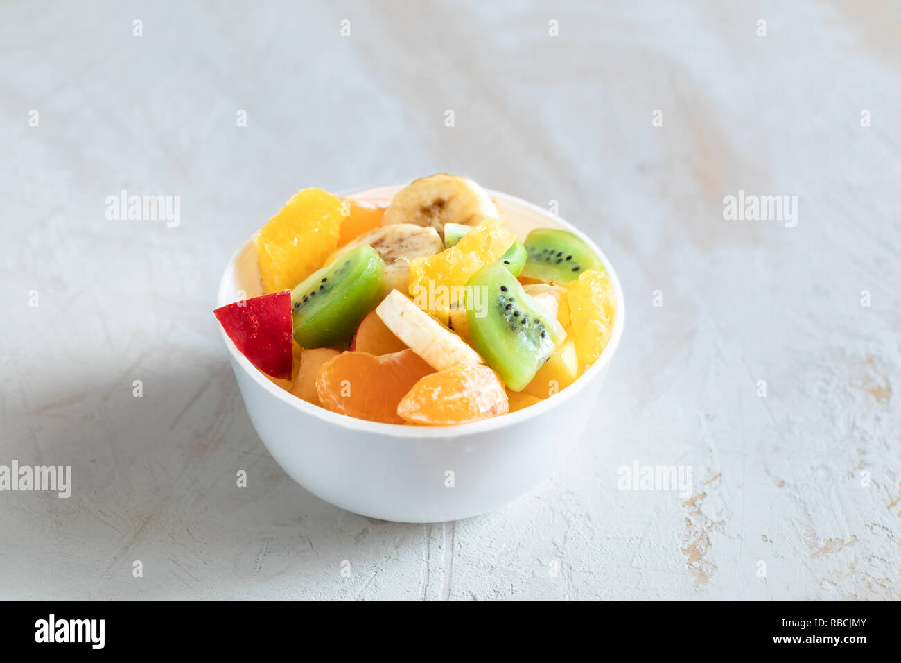 Ciotola bianco con insalata di frutta è in piedi in mezzo di sfondo bianco. Foto Stock