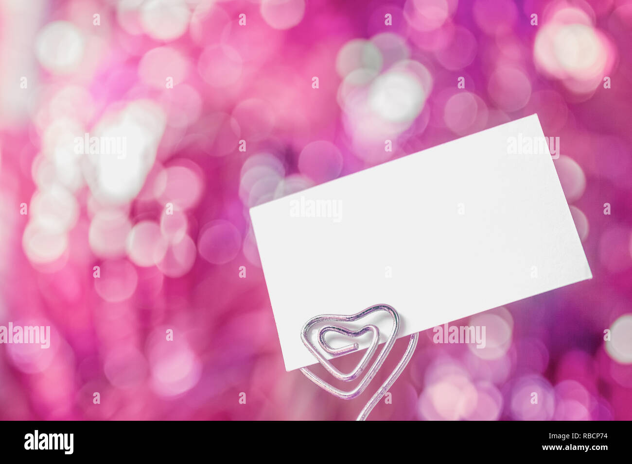 Vuoto vuoto bianco carta nota sul dolce sfocata bokeh sfondo rosa. Spazio libero per qualsiasi testo di design. Valentines il concetto di sfondo. Soft Focus. Foto Stock