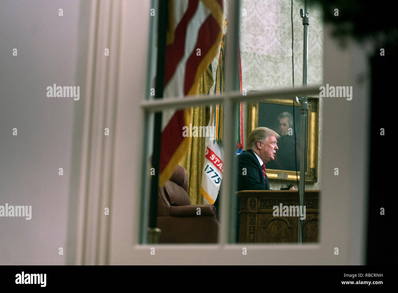 Washington, Stati Uniti d'America. 08 gen 2019. Presidente Donald Trump è visto attraverso la finestra dell'Ufficio ovale come egli offre un indirizzo primetime sul governo di spegnimento e la sua richiesta di finanziamenti per oltre 5 miliardi di dollari per un confine meridionale del muro, alla Casa Bianca di Washington, DC Credito: Kevin Dietsch/Piscina via CNP | Utilizzo di credito in tutto il mondo: dpa/Alamy Live News Foto Stock