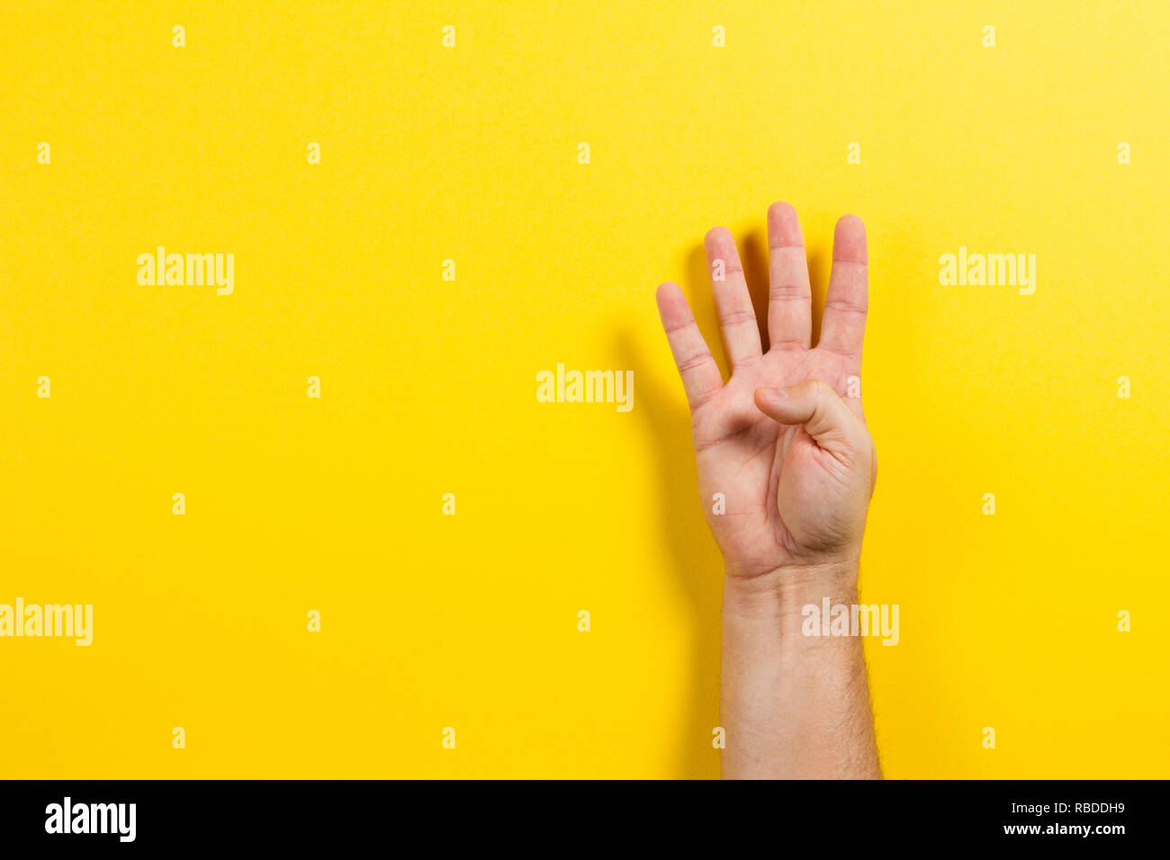 Man mano che mostra quattro dita su sfondo giallo. Il numero due simbolo Foto Stock
