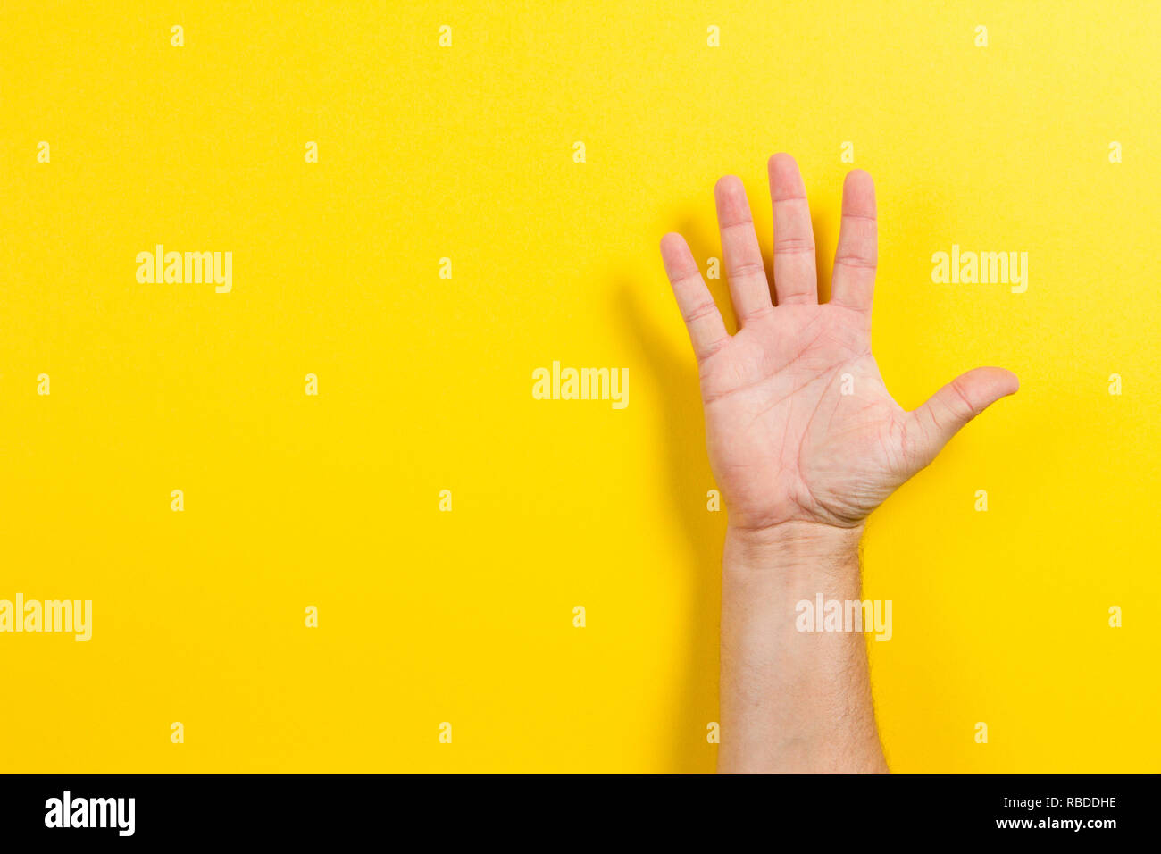 Man mano che mostra cinque dita su sfondo giallo. Il numero due simbolo Foto Stock