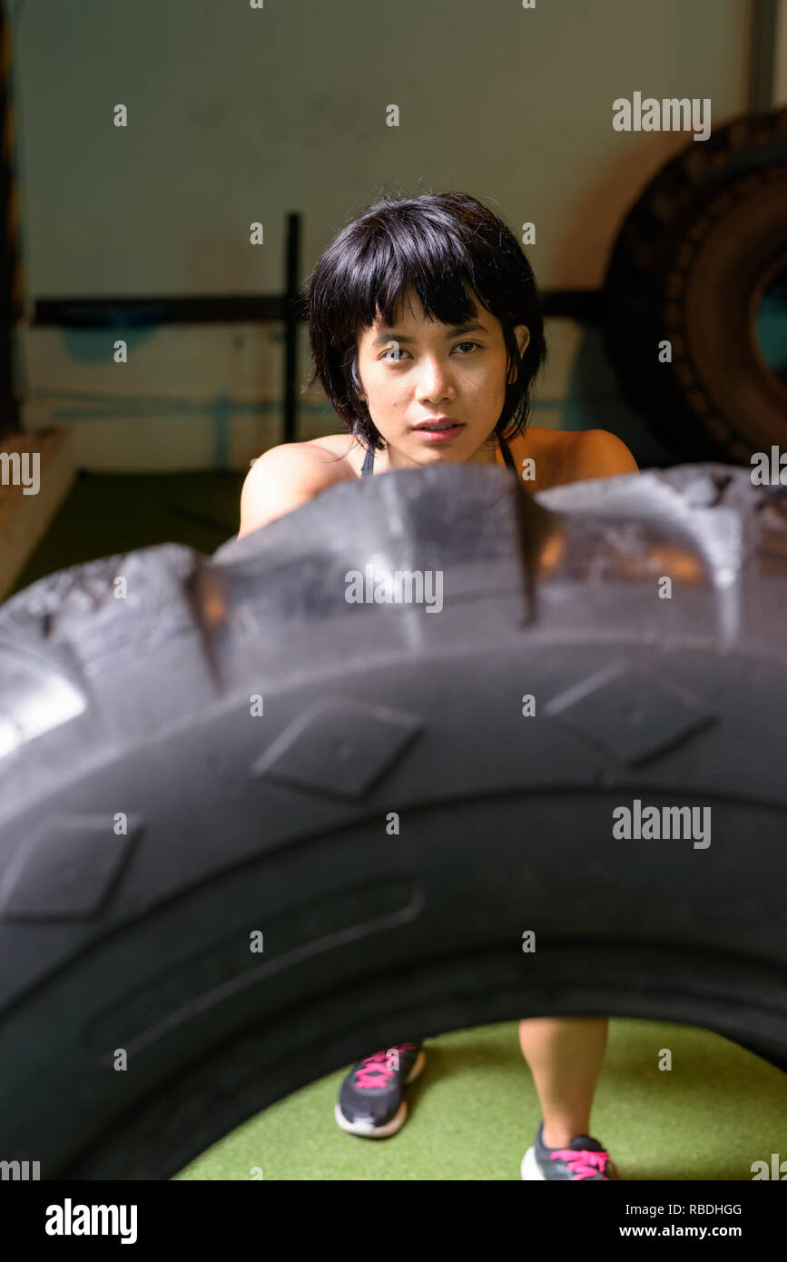 Asia donna fitness di spinta e di ribaltamento ruota carrello pneumatico in palestra Foto Stock