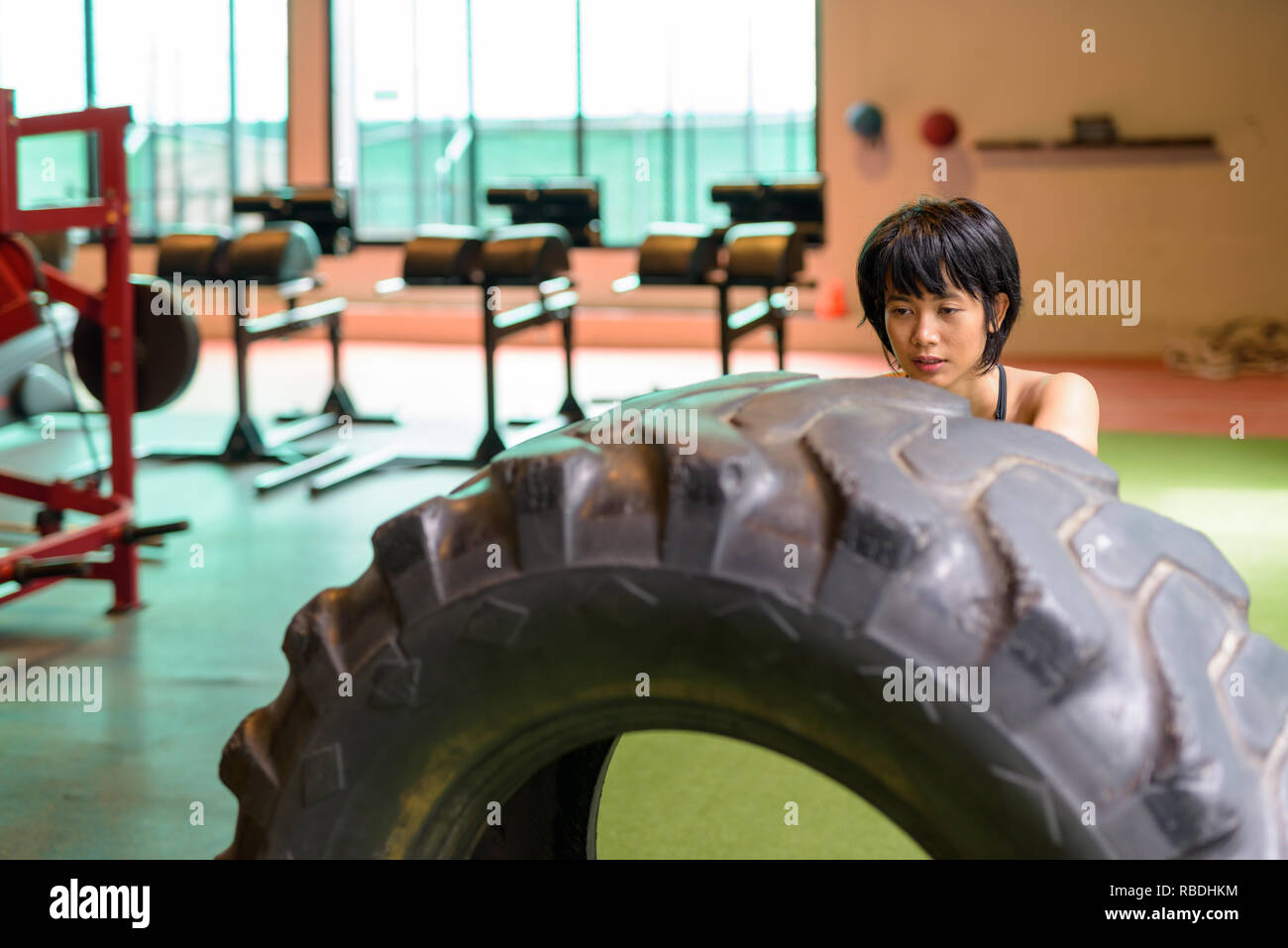 Asia donna fitness di spinta e di ribaltamento ruota carrello pneumatico in palestra Foto Stock