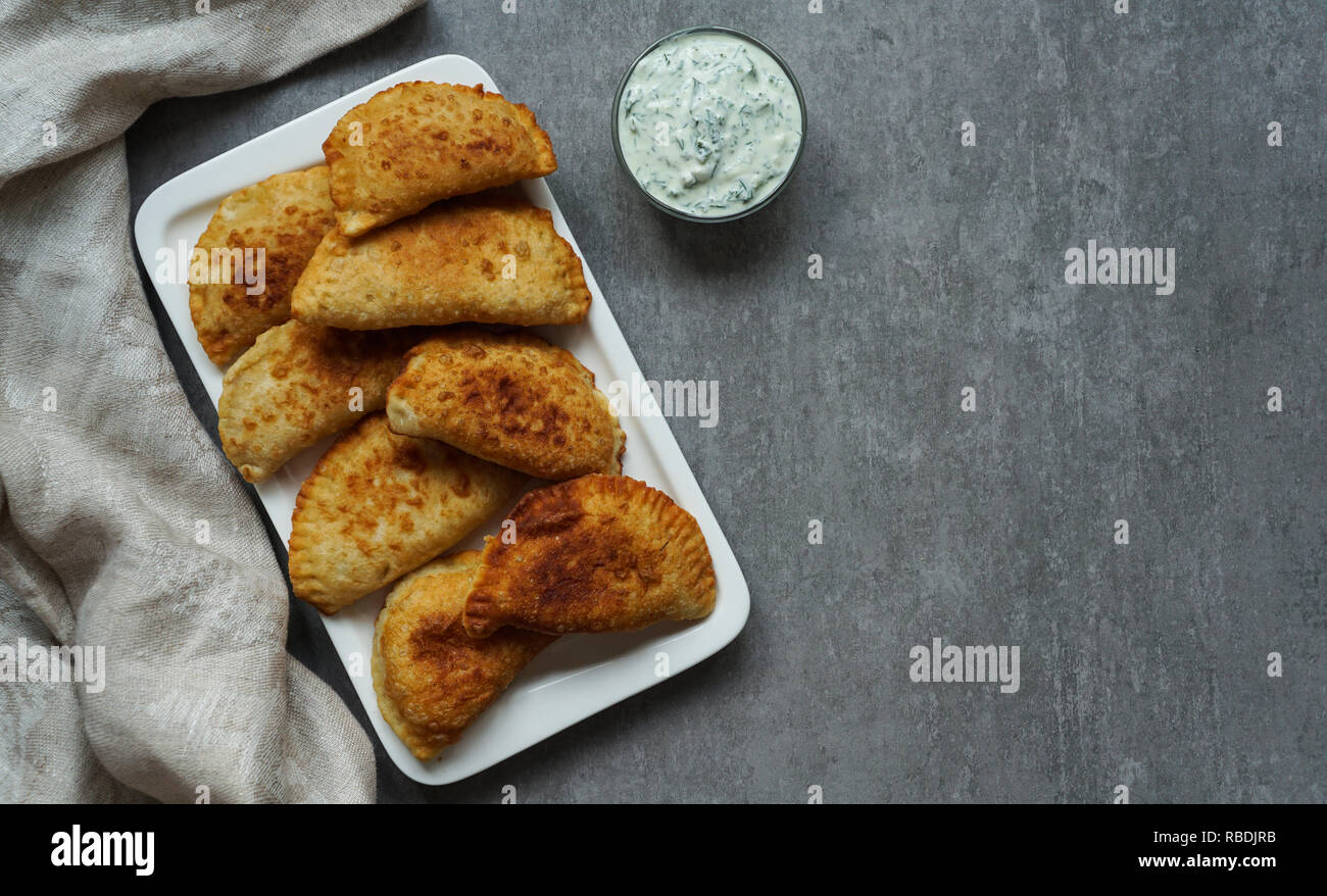 Spagnolo e latino-americano empanadas fritto con salsa sulla pietra grigia sfondo, vista dall'alto Foto Stock