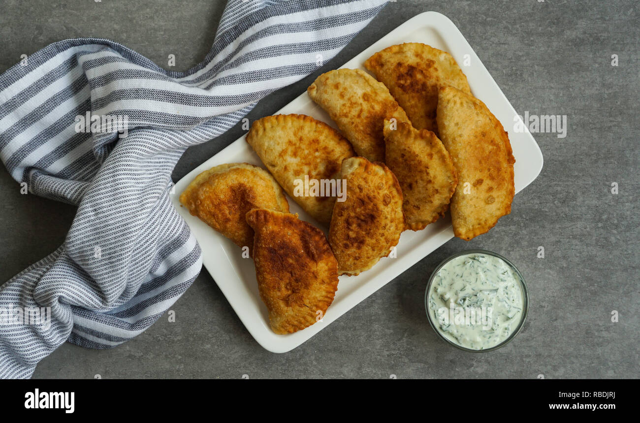 Spagnolo e latino-americano empanadas fritto con salsa sulla pietra grigia sfondo, vista dall'alto Foto Stock