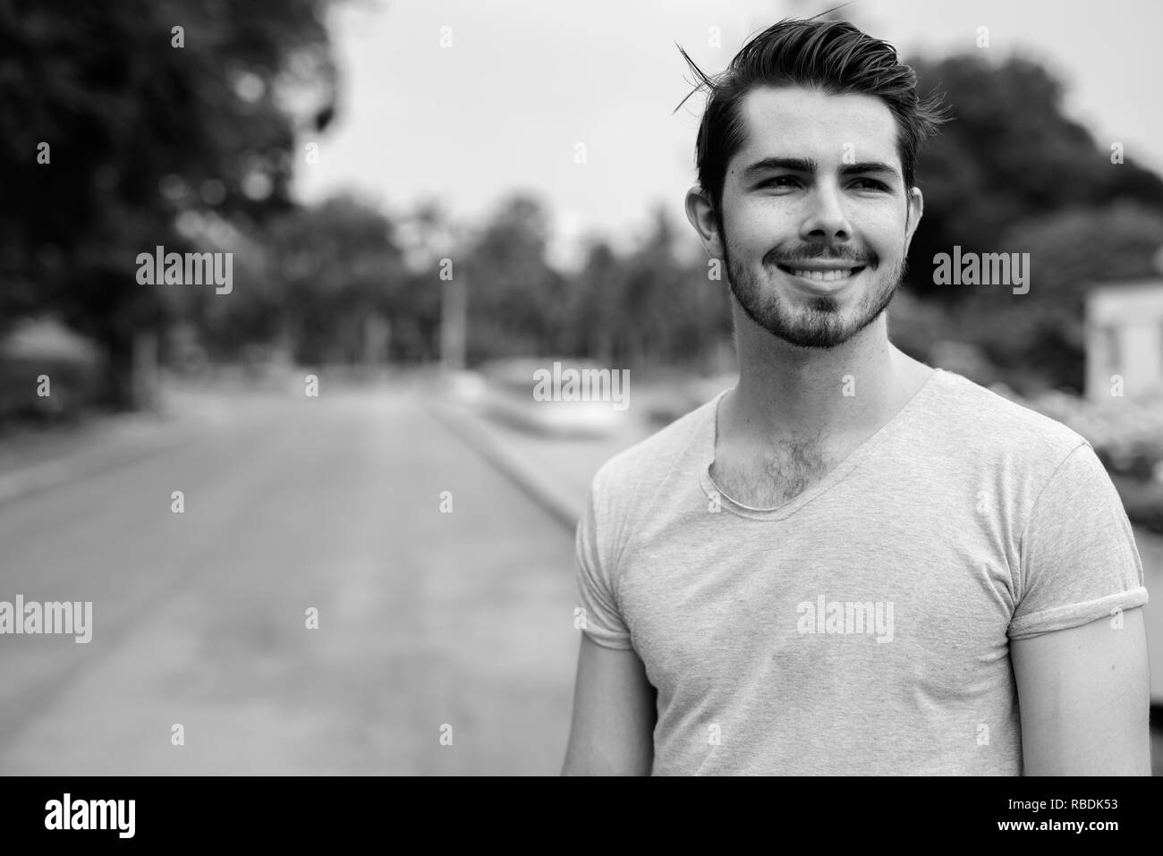 Ritratto di giovane uomo bello rilassarsi presso il parco in bianco e nero e Foto Stock