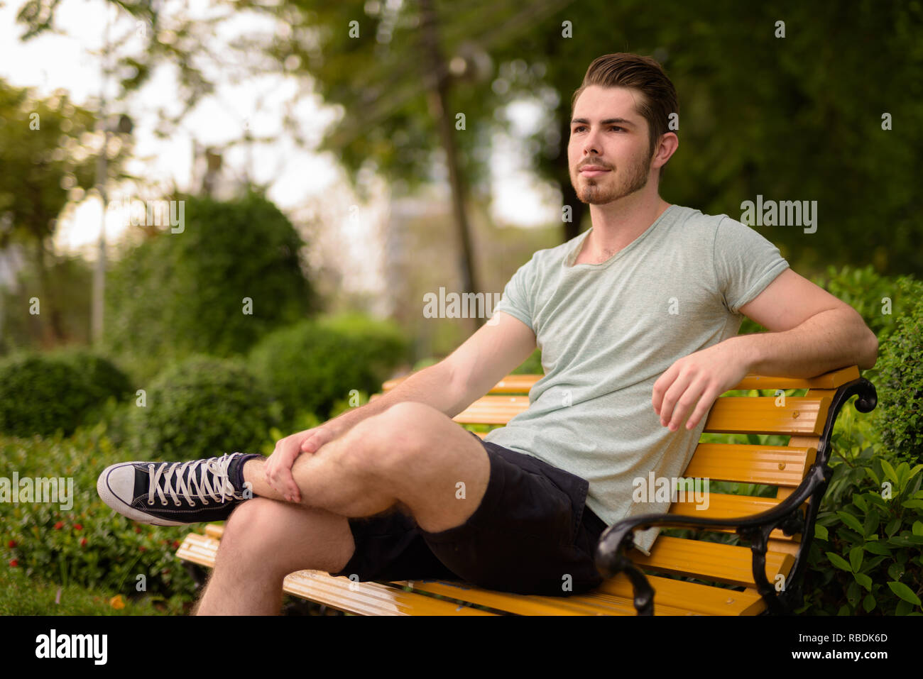 Ritratto di giovane uomo bello seduto in posizione di stazionamento mentre il pensiero Foto Stock