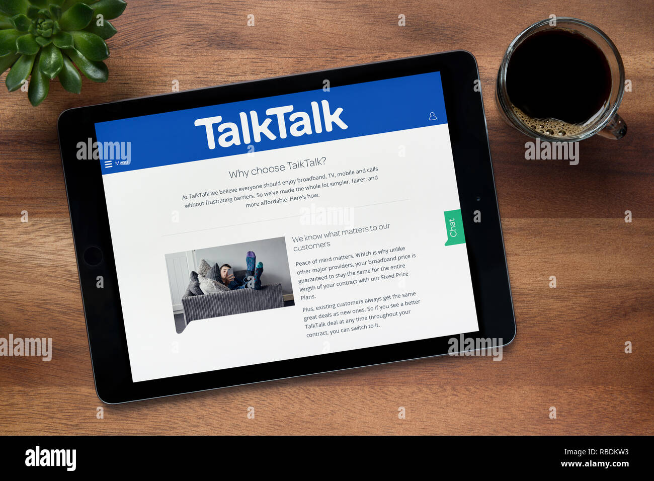Il sito web di TalkTalk è visto su un tablet iPad, su di un tavolo di legno lungo con un caffè espresso e una pianta di casa (solo uso editoriale). Foto Stock