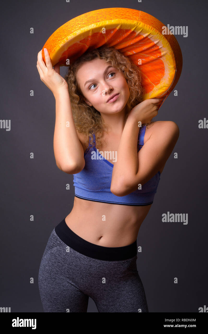 Giovane donna bellissima azienda grande fetta di frutta di arancia Foto Stock