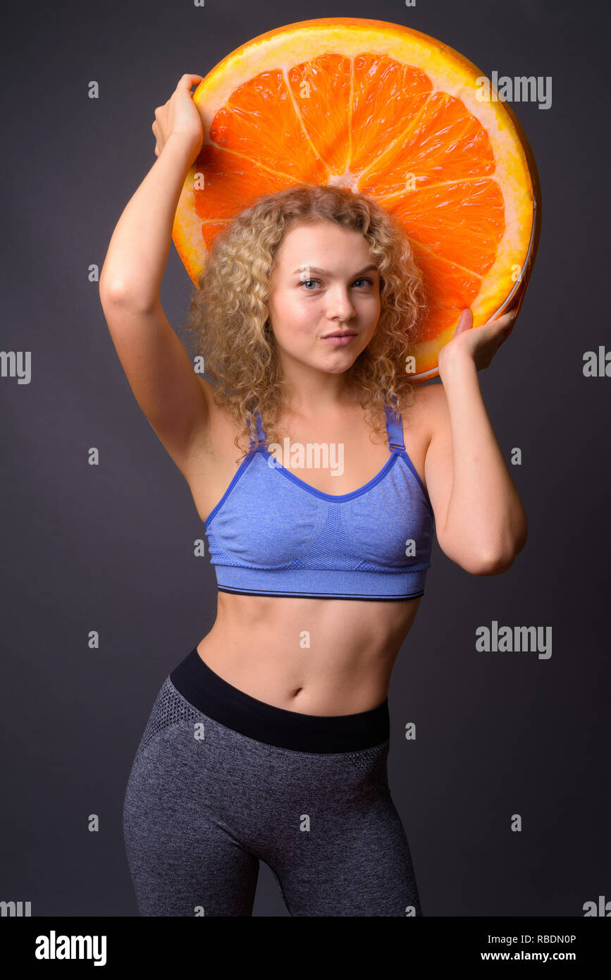 Giovane donna bellissima azienda grande fetta di frutta di arancia Foto Stock