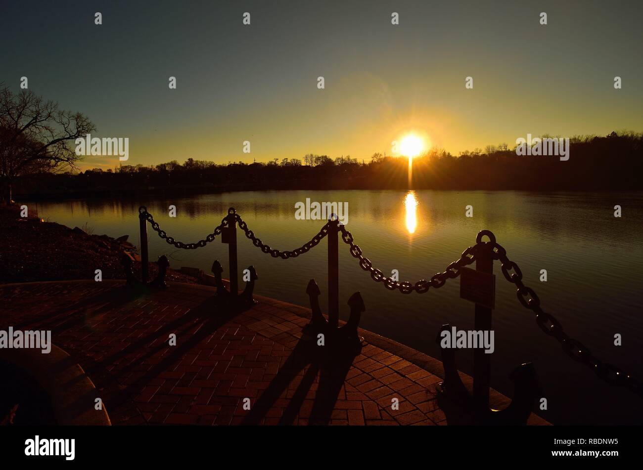 Elgin, Illinois, Stati Uniti d'America. Sunset riflettendo sul Fiume Fox come visto attraverso gli ancoraggi a Veterans Memorial Park della città. Foto Stock