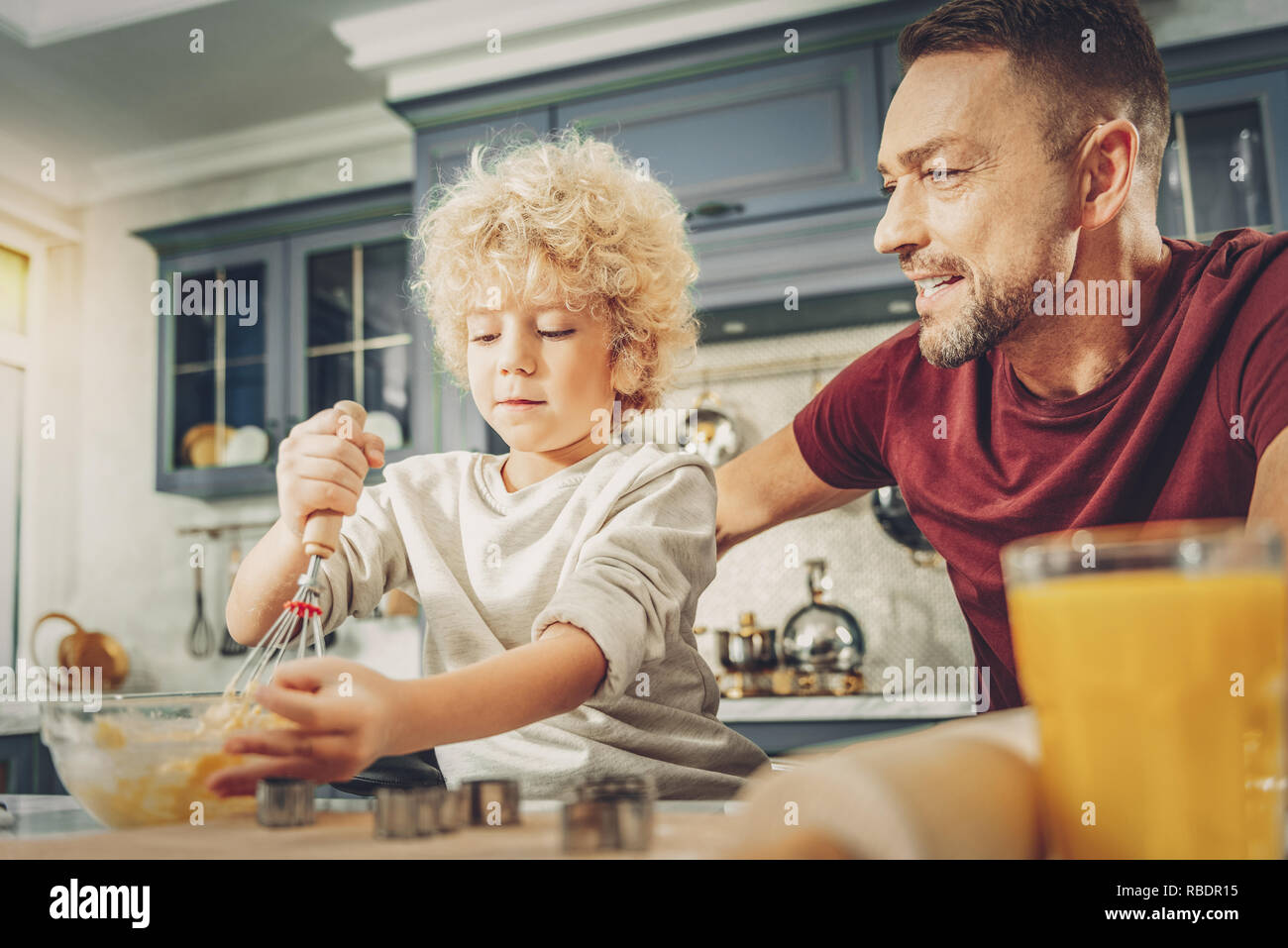 Senza mani. Basso angolo di concentrato di bel ragazzo di miscelazione e impasto uomo dandogli consulenza Foto Stock