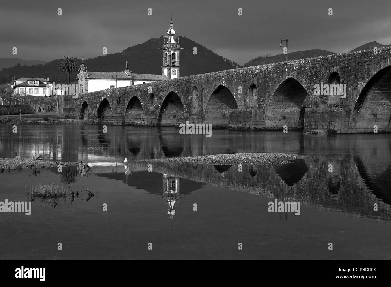 Ponte de Lima città medievale Ponte e riflessione contro dark sky piovosa. Convertito in bianco e nero. Foto Stock
