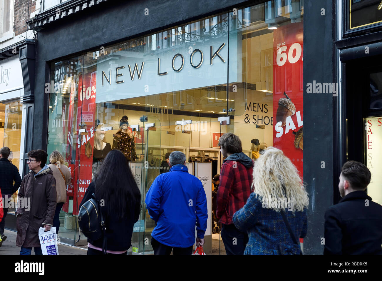Gli amanti dello shopping a camminare lungo il ramo di Chester del nuovo look con segni di vendita nella finestra Foto Stock