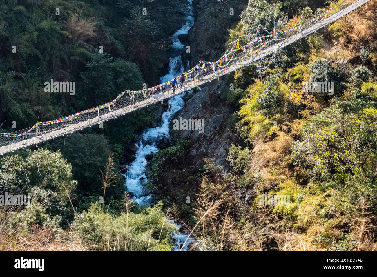 Due persone attraversando un ponte di sospensione ona percorso di trekking in Langtang National Park, Nepal Himalaya Foto Stock