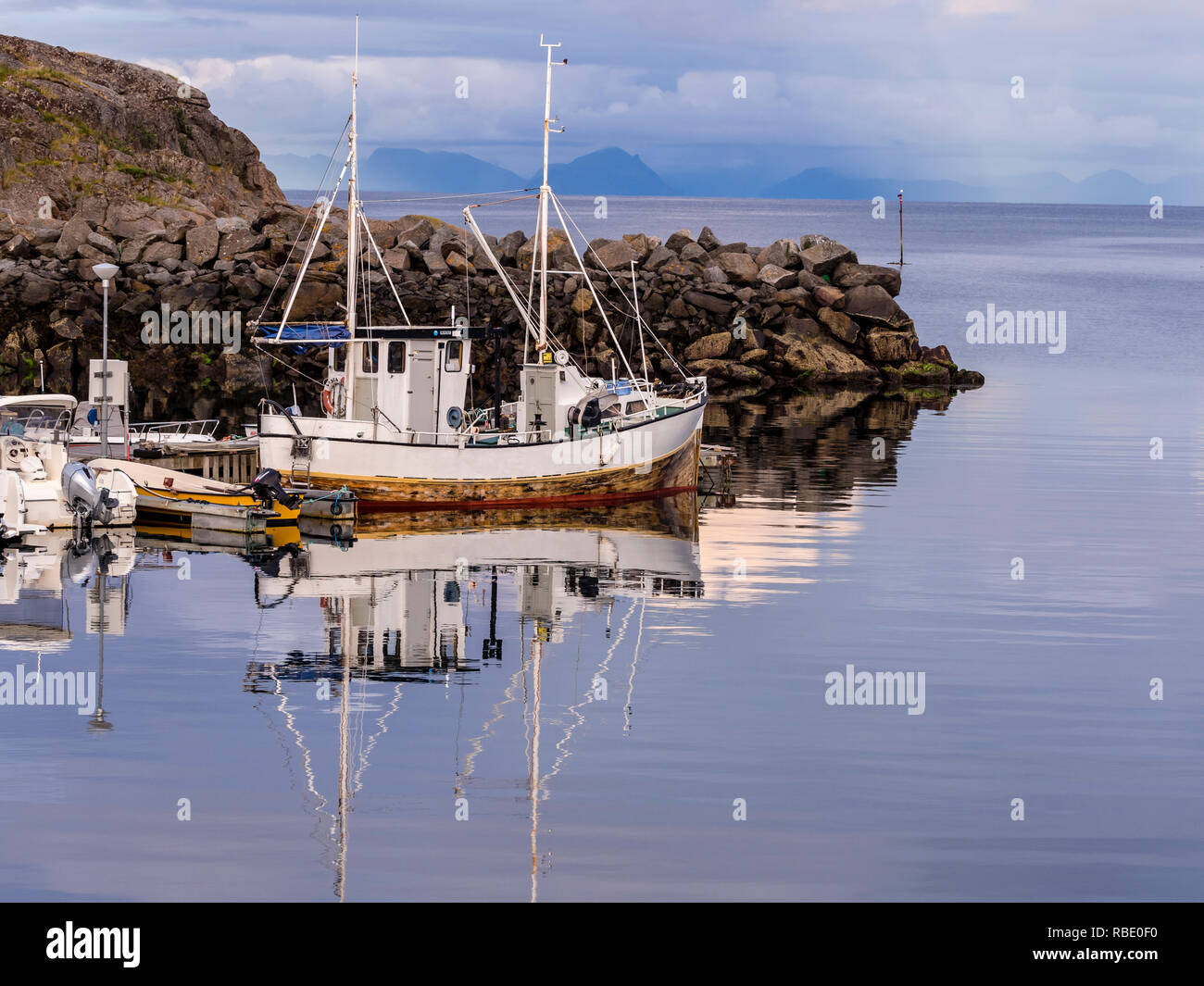 Barca da pesca nel porto di Stamsund, riflessi sul mare calmo, isole Lofoten, Norvegia Foto Stock