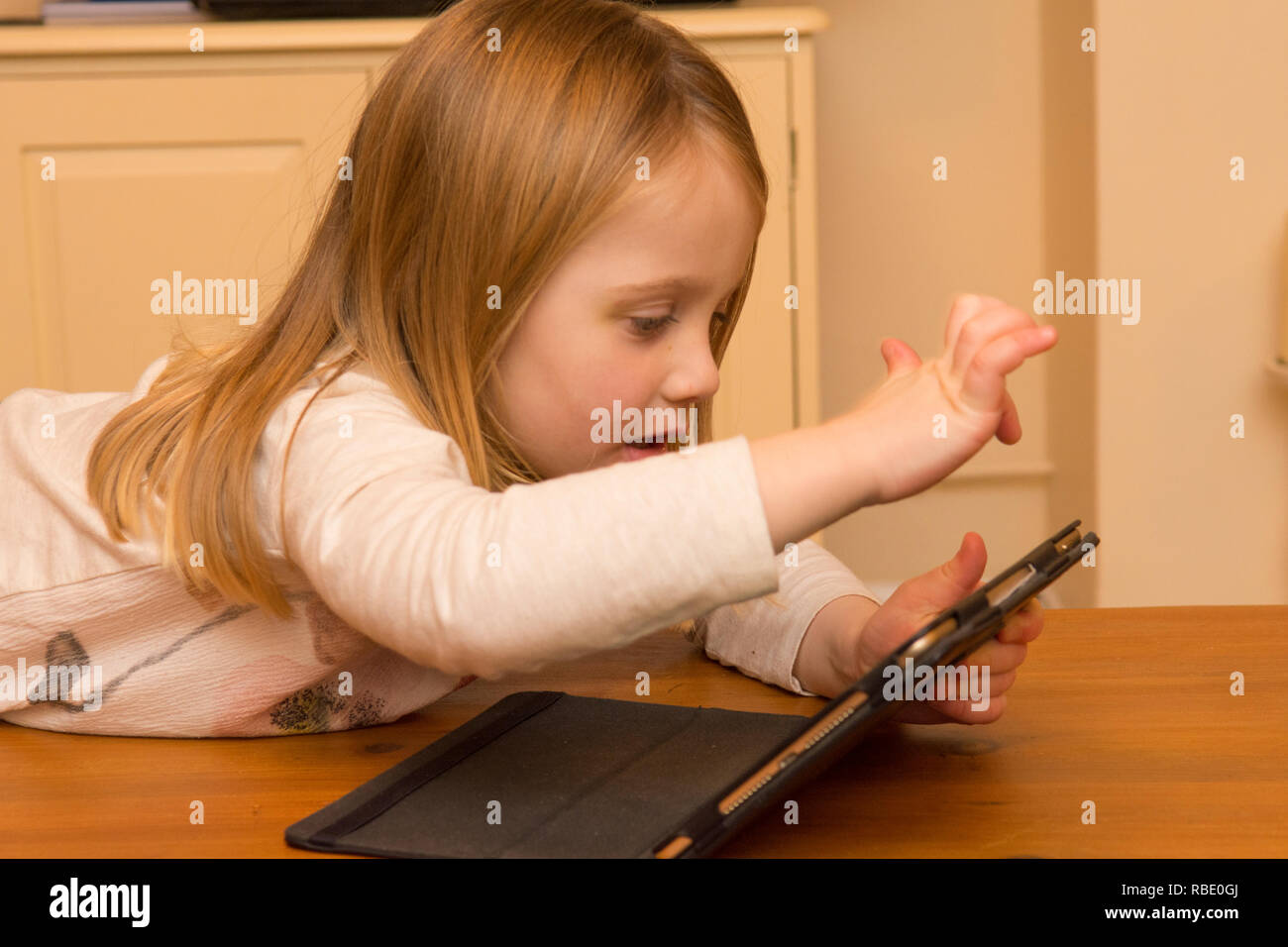 Ragazza giovane giocando con una pastiglia, dispositivo digitale, iPad schermo, bimbo di tre anni Foto Stock