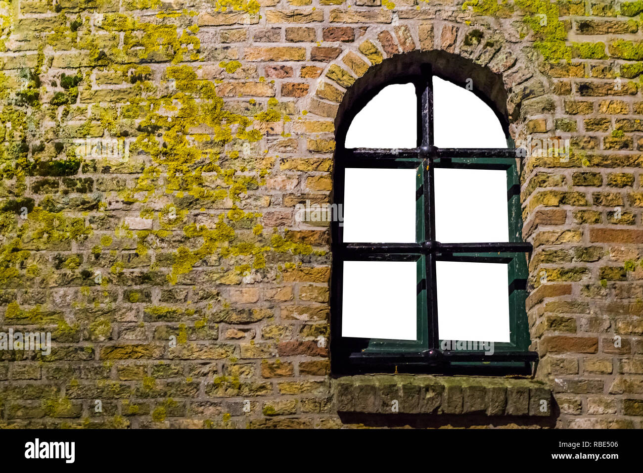 Mossy muro di mattoni con una vecchia finestra in legno telaio quadro vuoto isolato su bianco Foto Stock